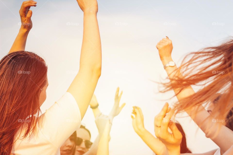 Group of young happy dancing tan girls on blue sky background, summer time, open air party