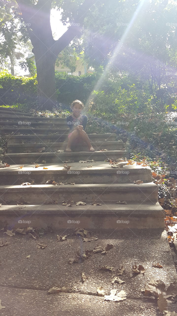 Little happy girl sitting on steps in park