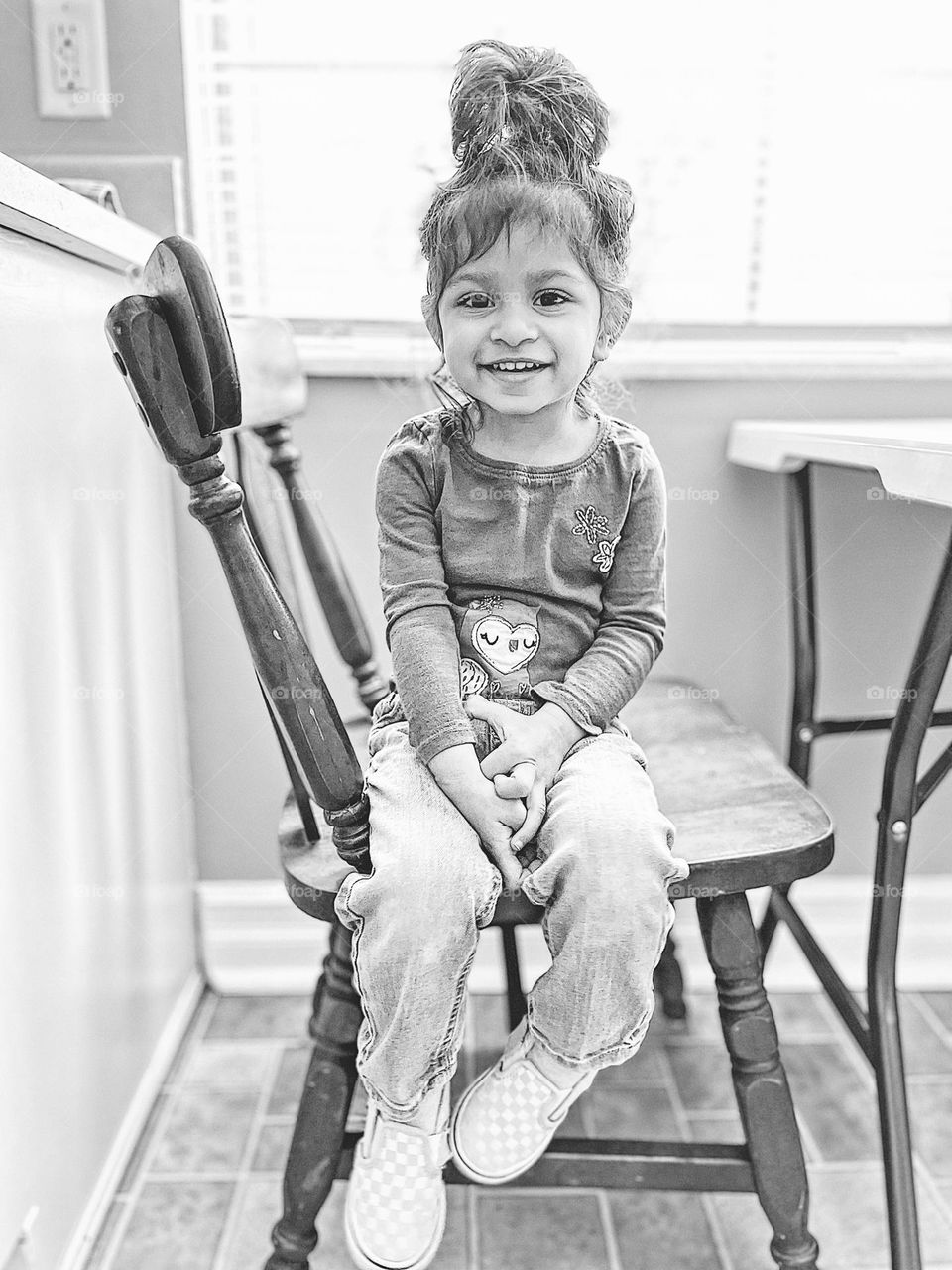 Monochrome portrait of a toddler, toddler sitting on a chair, toddler girl smiling for camera, toddler sits on a chair proudly