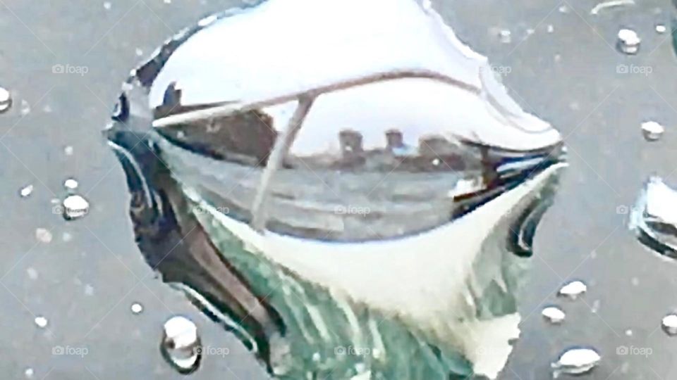 An extremely unusual photograph of a puddle of water that formed on the back deck of our sailboat, the “Salvation” and mirrors in it the shore at Newtown Creek, LIC, Queens, NY of the Greenpoint, Bklyn side. 2021. Hypnotic Productions