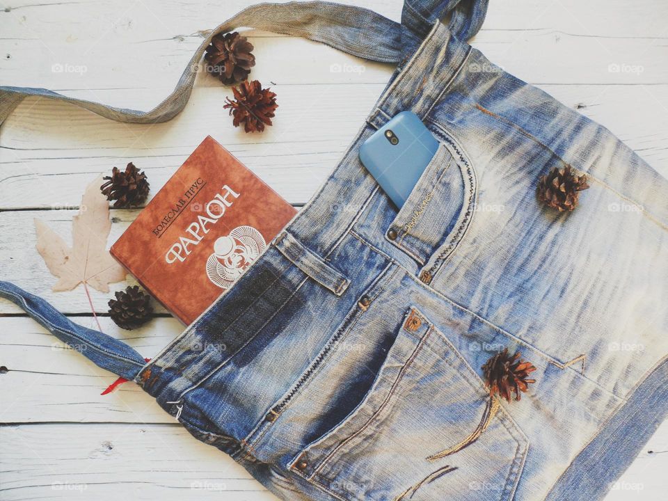 denim bag, book and smartphone are on the table