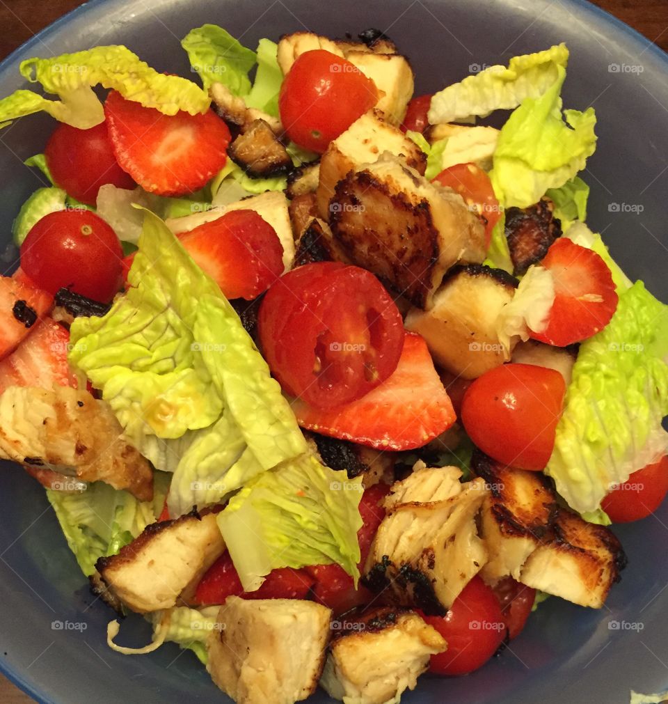 A colorful salad with strawberries, lettuce, grilled chicken, cherry tomatoes and celery.