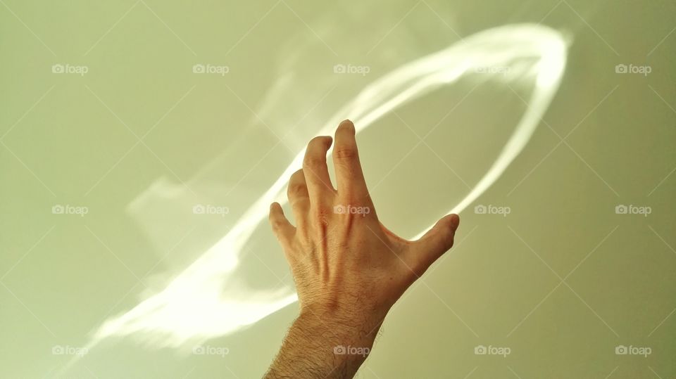 a hand holding a sparkle of sunshine flashing off the wall