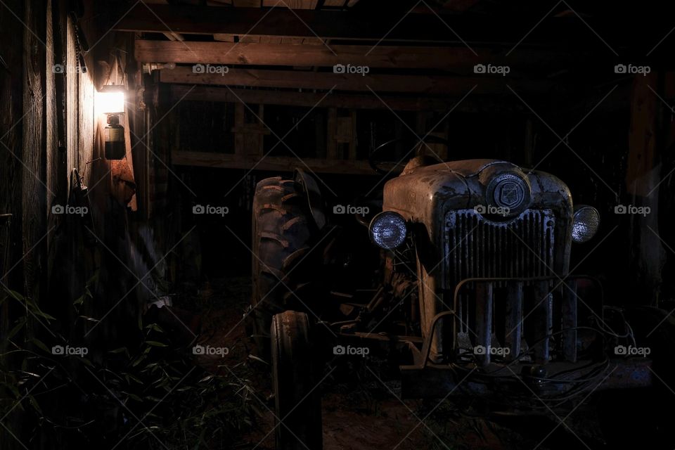 Front view A 1953 Ford Jubilee vintage tractor in dim lantern light in a barn that is still operational. 