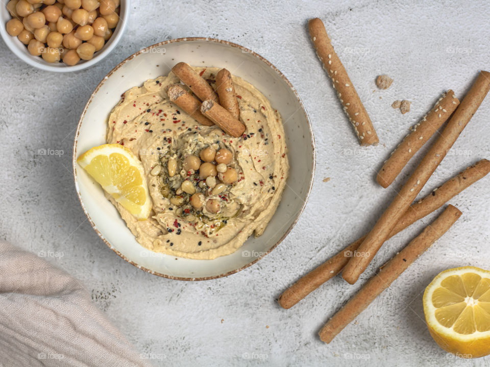 Hummus in a plate topped with chickpeas and bread sticks