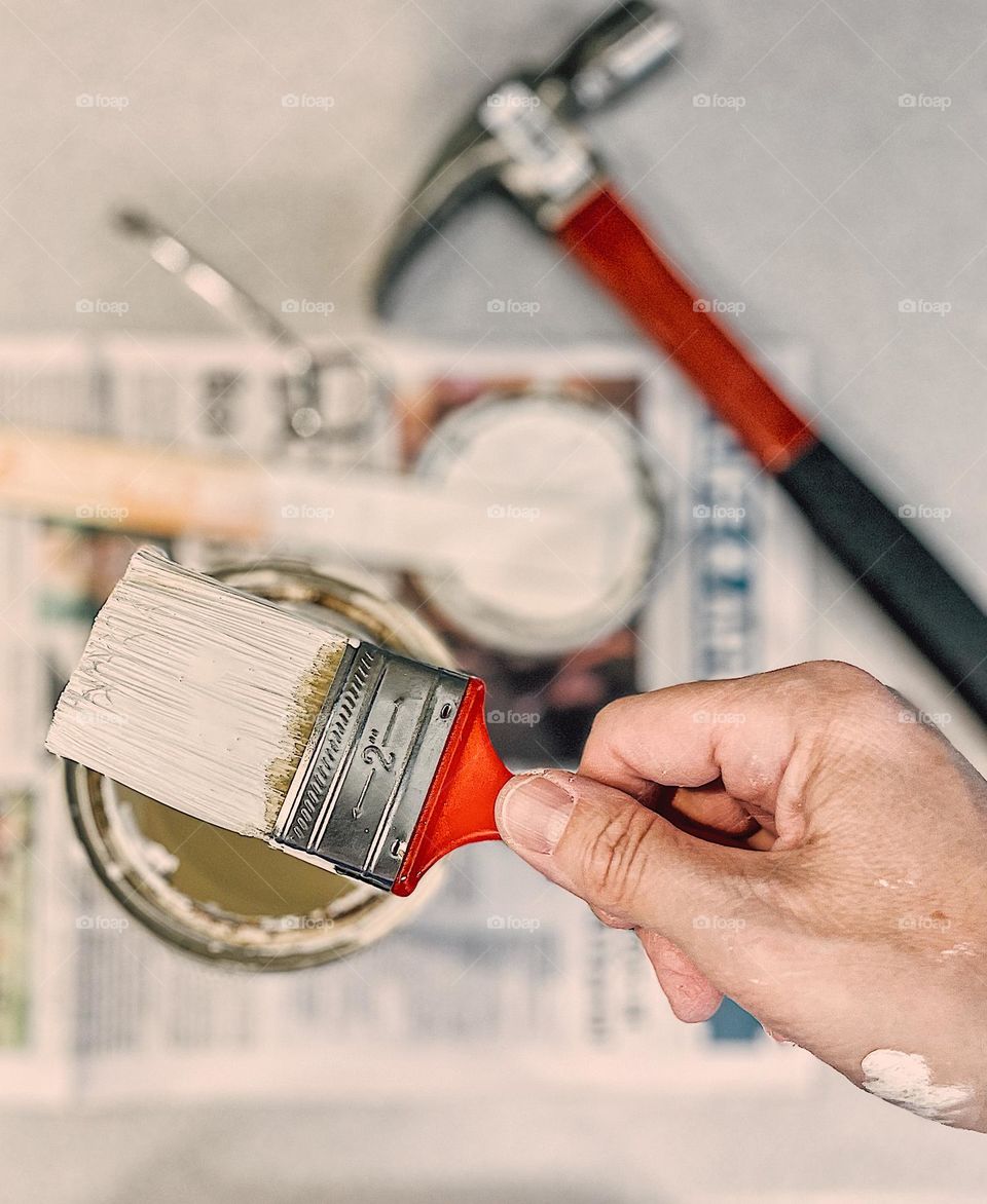 Woman’s hand holding paint brush with white paint on it, home improvement projects, working on my house, painting white walls, the tools of the trade, painting perspective 