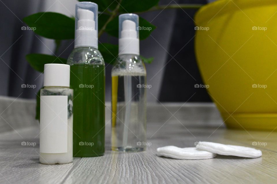 Jars with cream, shampoo and cosmetics on a background with green plants