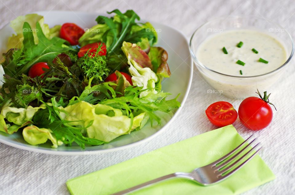 Colorful of fresh vegetables salad with sour cream salad dressing on served table.  Benefits lunch or dinner.