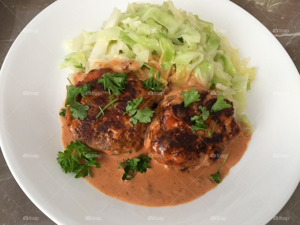 Beef patties with creamy tomato sauce and fried cabbage