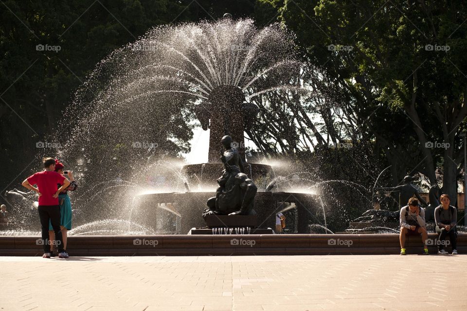 photo story People relaxing, talking, taking a photo of the fountain landmark at the park