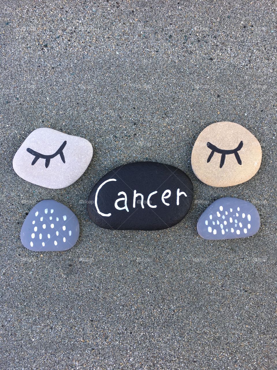 Cancer, conceptual stones composition over black sand 