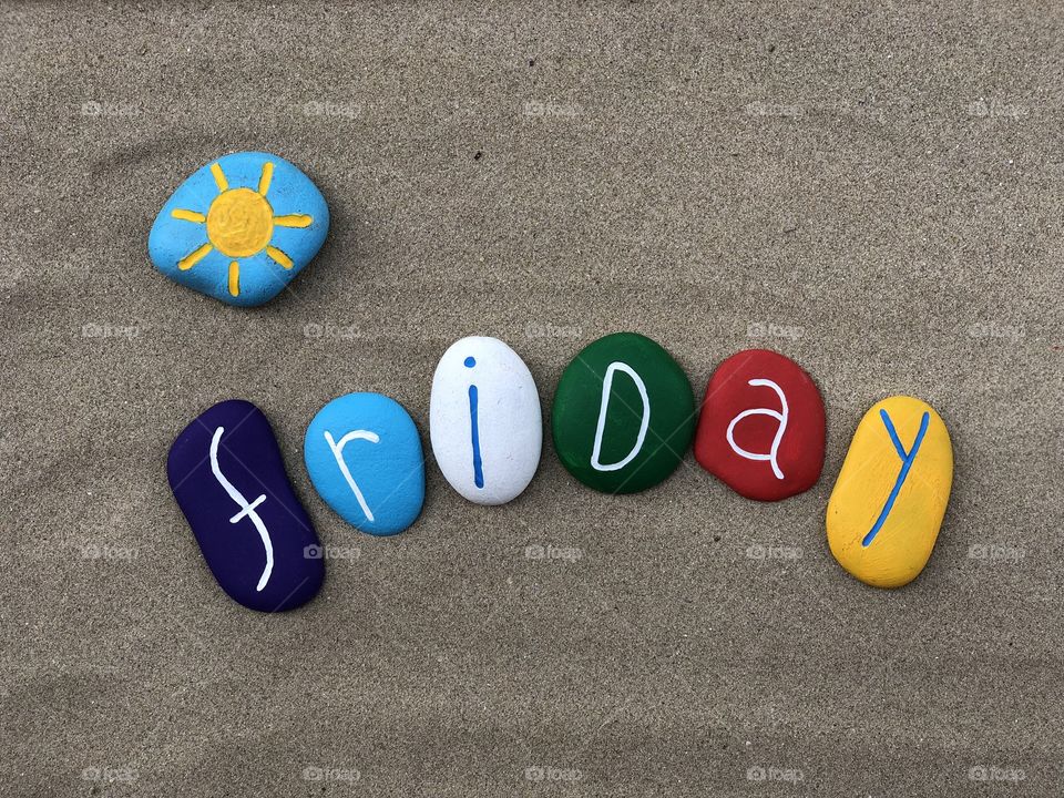 Friday, fifth day of the week with colored stones over beach sand