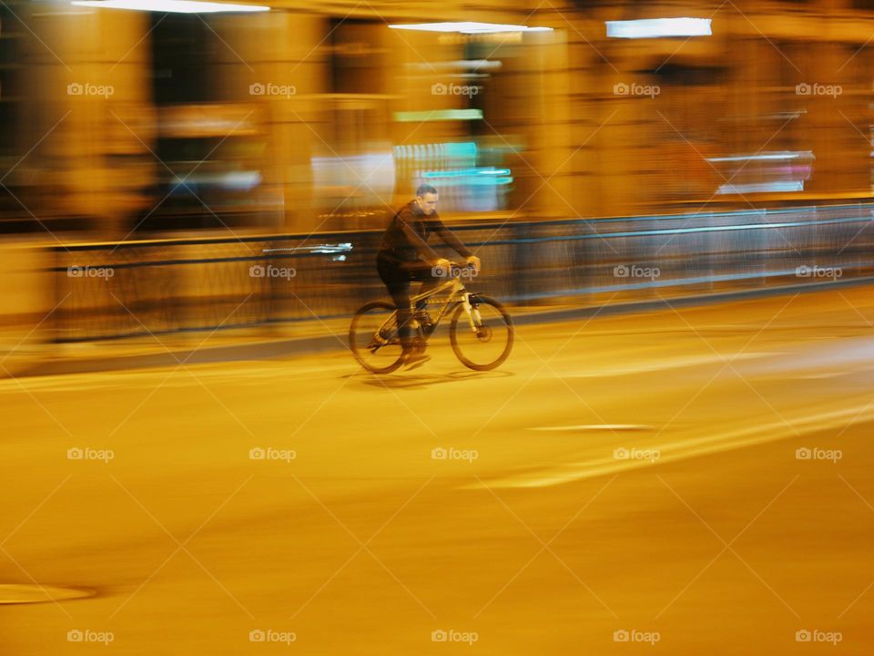 Men on a bicycle riding on night street, long exposure 