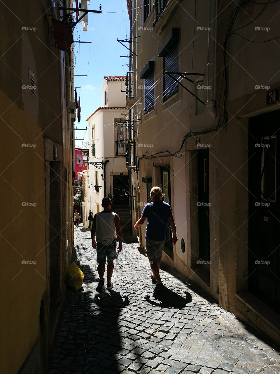 Two men walking in a narrow street in Alfama, Lisbon.