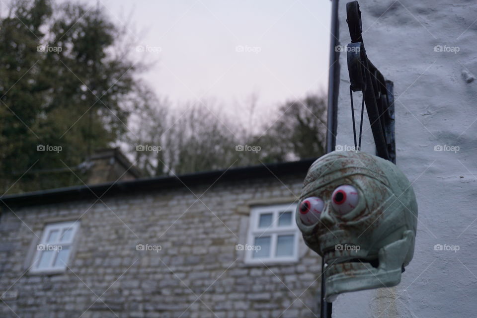 Spooky Halloween Decoration .. skeleton head hanging outside a house 
