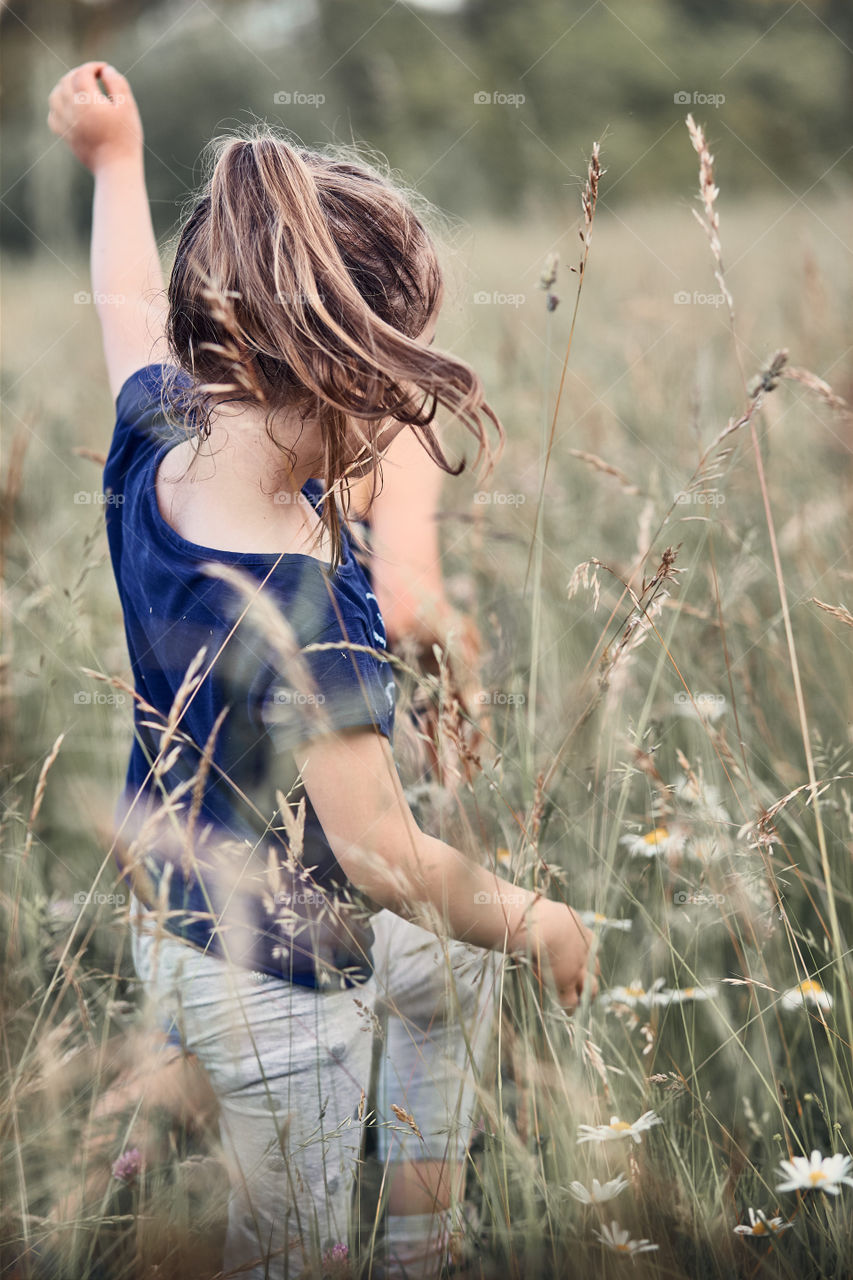 Little happy kids playing in a tall grass in the countryside. Candid people, real moments, authentic situations