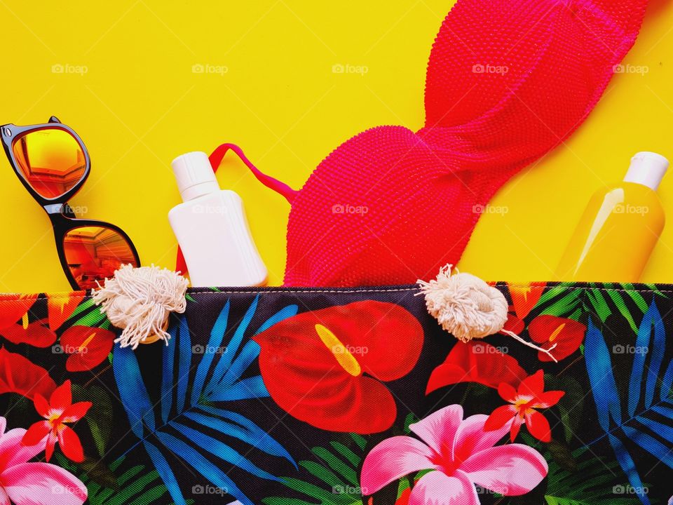 colored beach bag with sunscreen and neon pink bikini