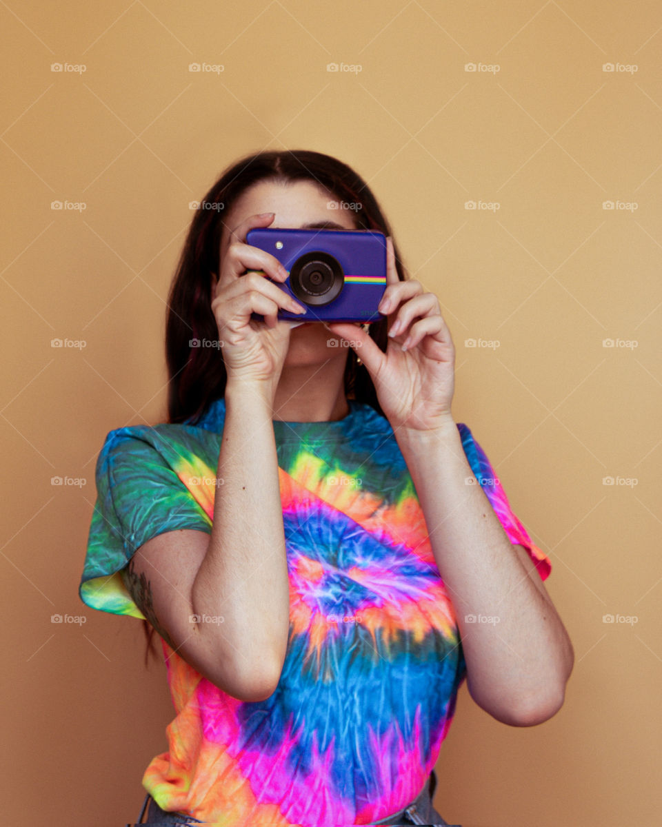 Woman in Tye dye shirt and polaroid Vintage camera