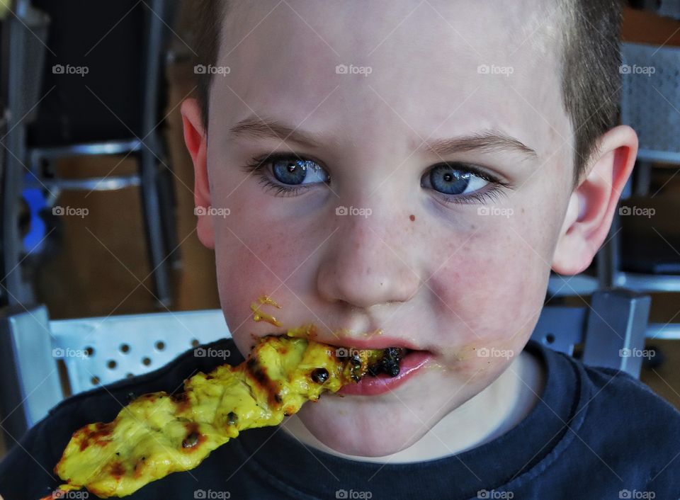 Boy Eating Chicken Skewer
