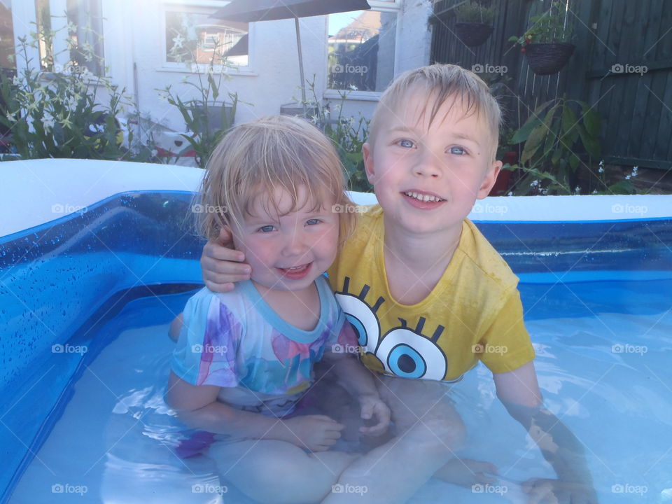 Two siblings sitting inside the inflatable tub