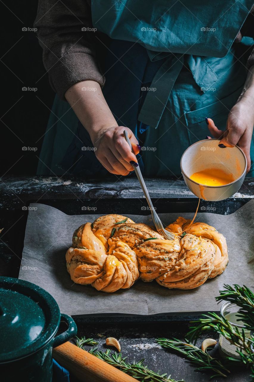 Women's hands, flour and dough. Levitation in a frame of dough and flour. A woman in an apron is preparing dough for home baking. Rustic style photo. Wooden table, wheat ears and flou.Emotional photo