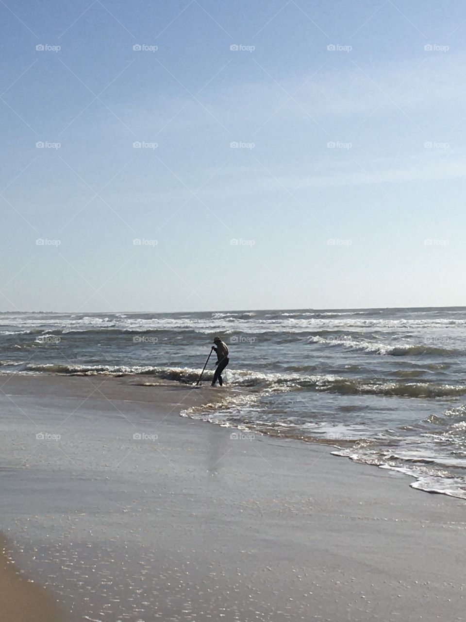 Man fishing shells at low tide