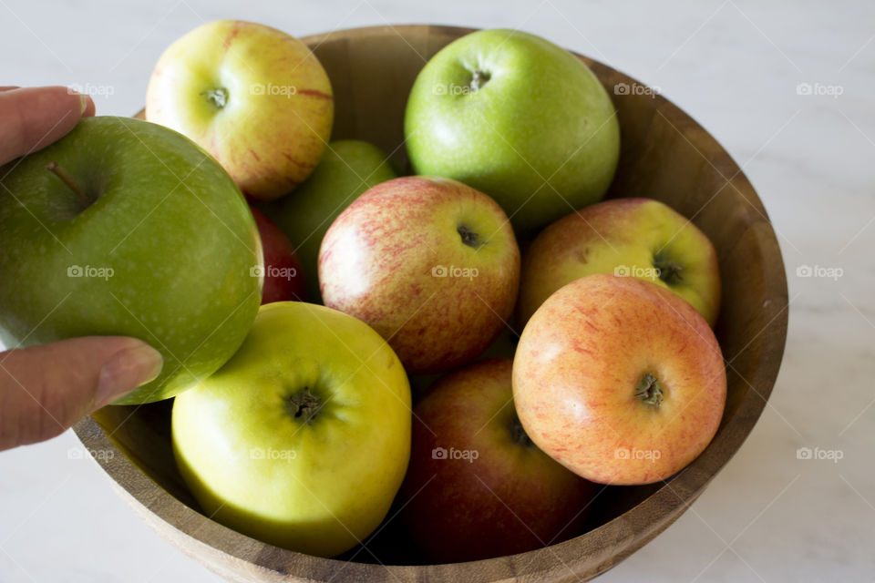 Taking one apple from wood bowl filled with apples 