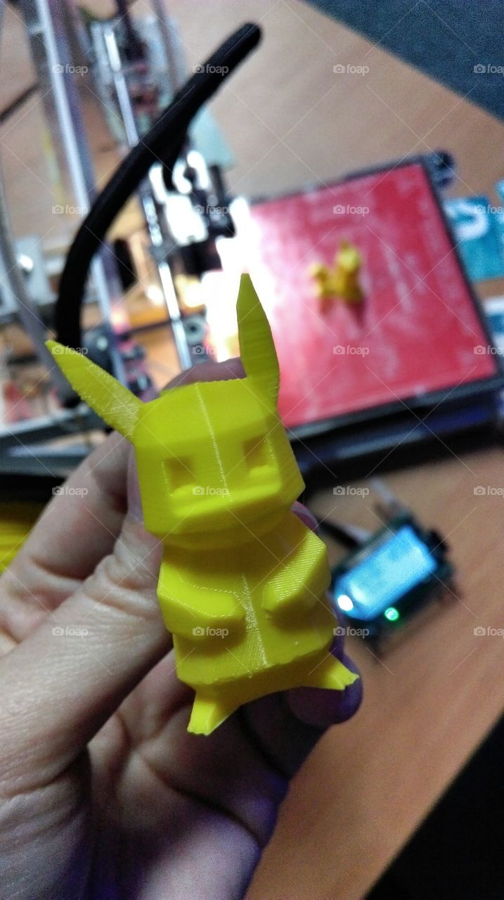 3D printed toy. Hand holding 3D printed yellow toy