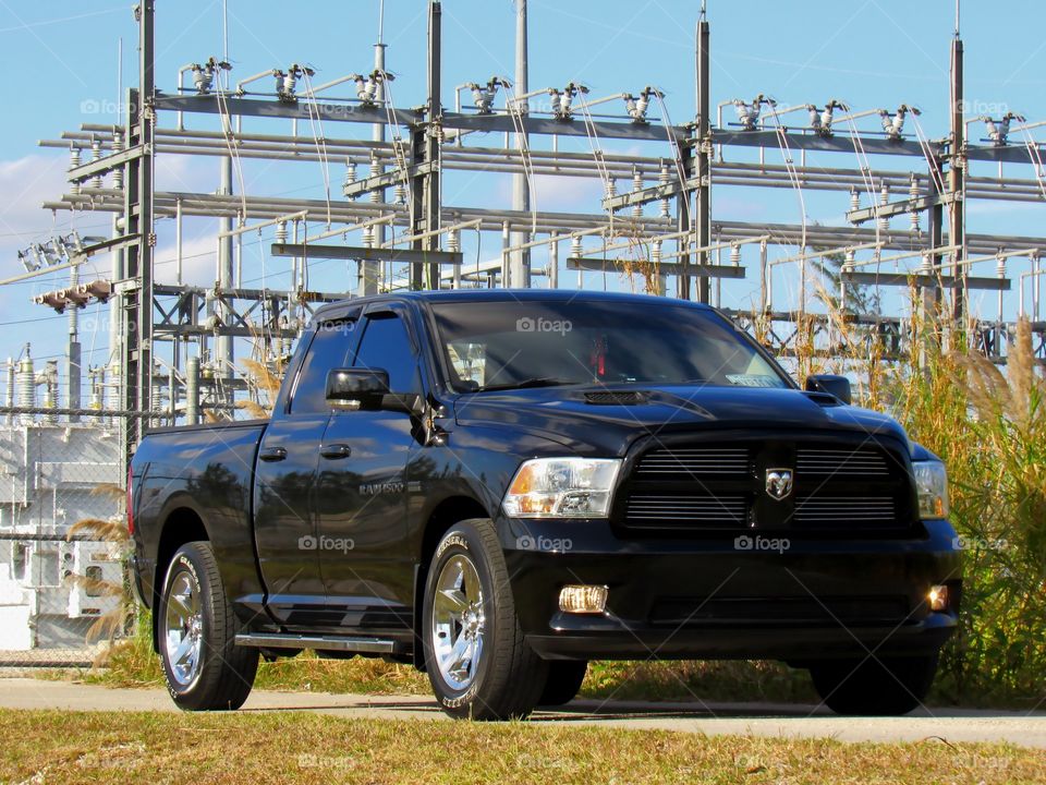 A Dodge Ram on the side of the road by a power grid.
