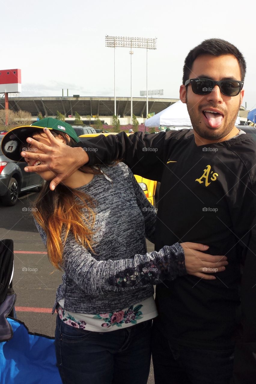 Funny young couple - guy jokingly pushes girl’s face away while making a silly face with his tongue out