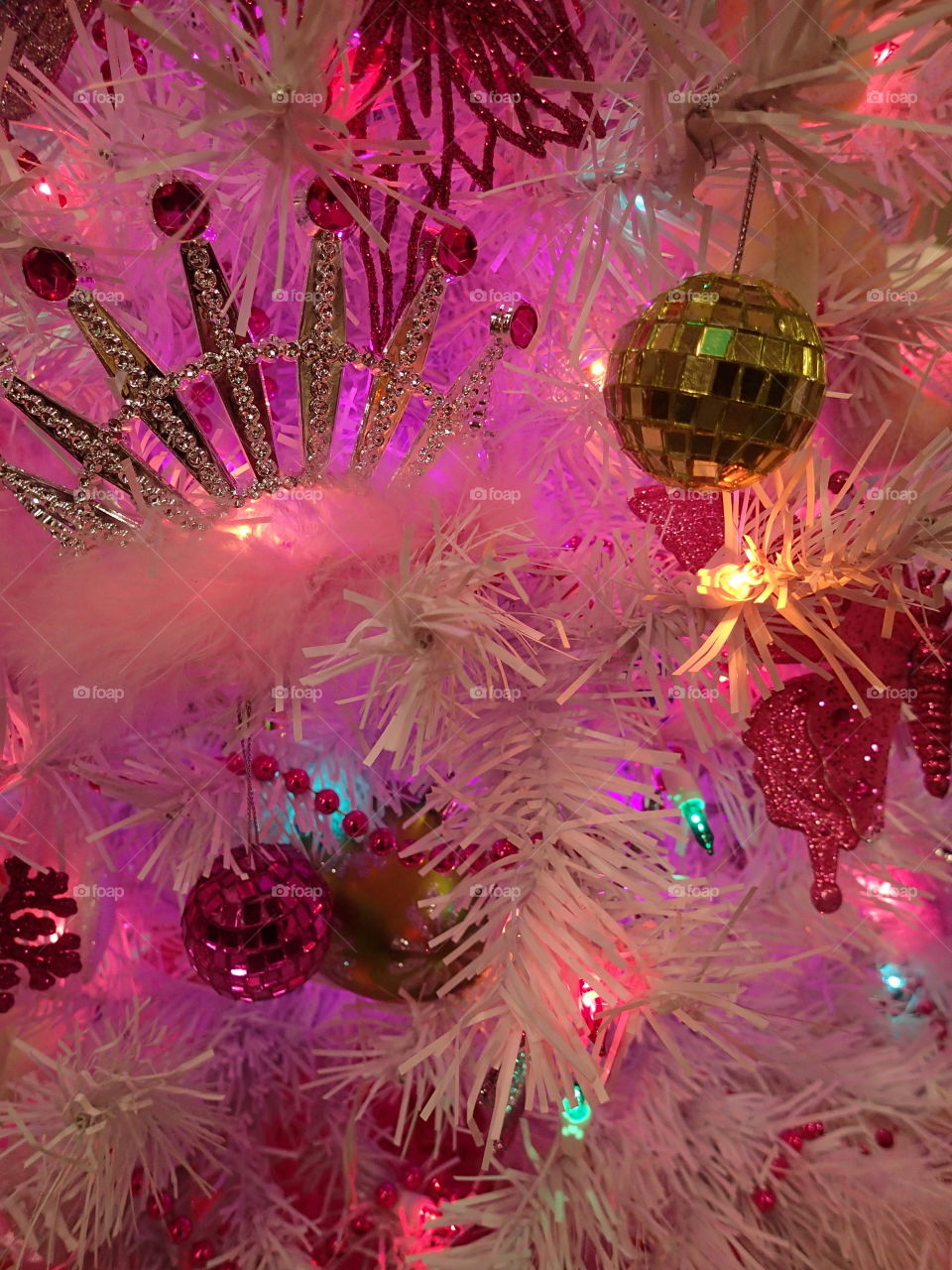 A white Christmas tree with pink lighting and golden ornaments. 