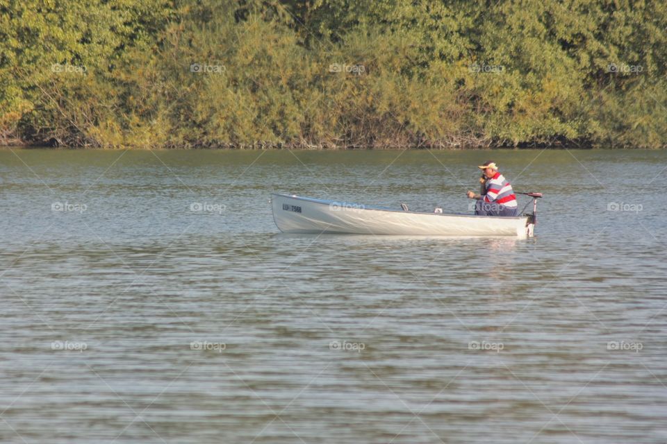 Fisherman On Cellphone. Man talking on his cellphone while fishing in the lake.