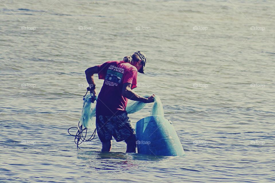 Fisherman in the ocean netting fish for dinner.