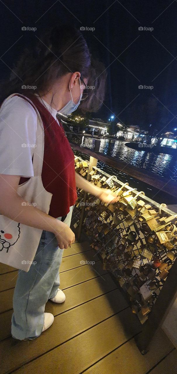 A young girl checking names engraved on promise bridge locks 🔒