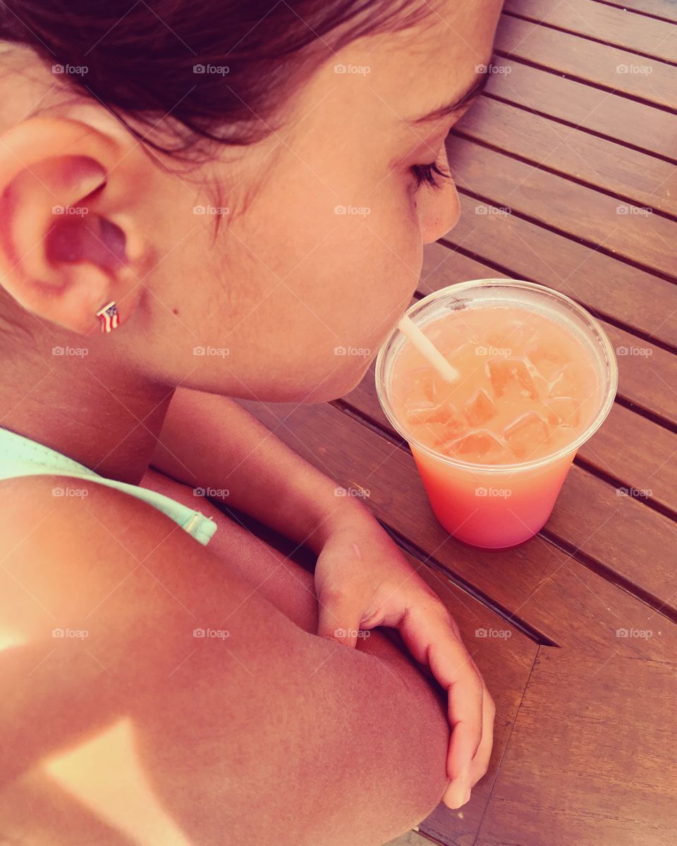 High profile of girl drinking summer drink through straw