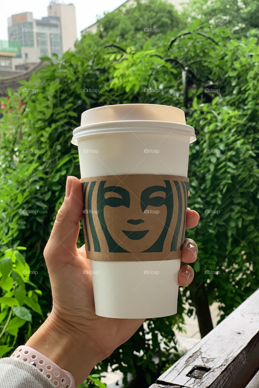 Hand holding cup of coffee from Starbucks 