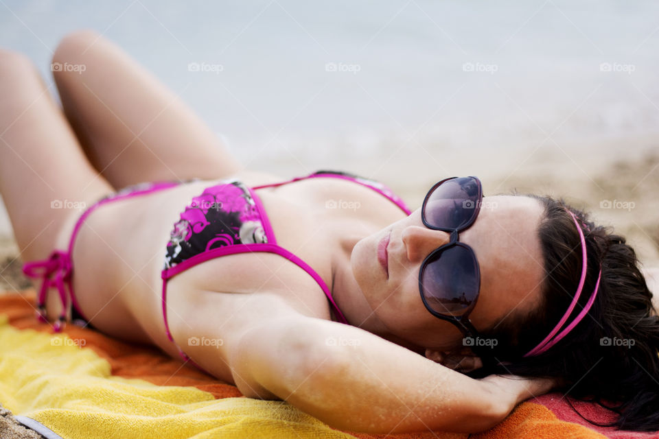 Young woman lying on beach in bikini