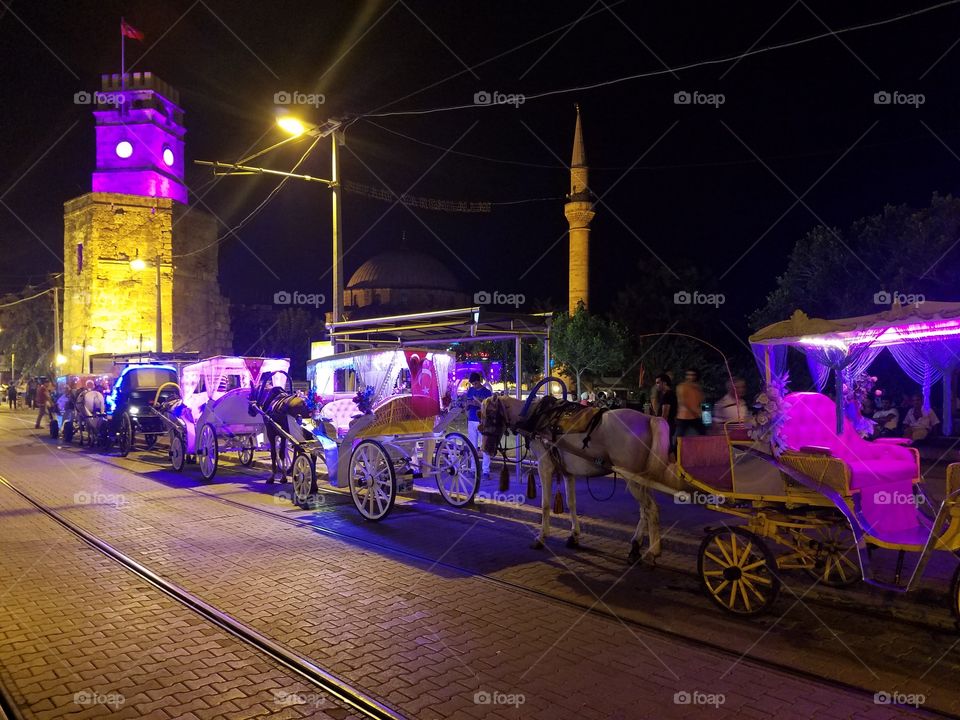 horse carriages line the streets in front of the clock tower in old town antalya turkey