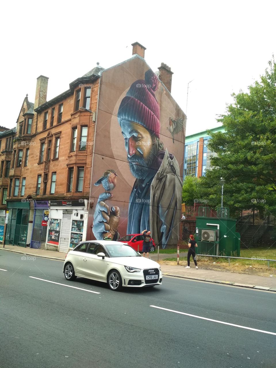 A car on the road passing by a mural
