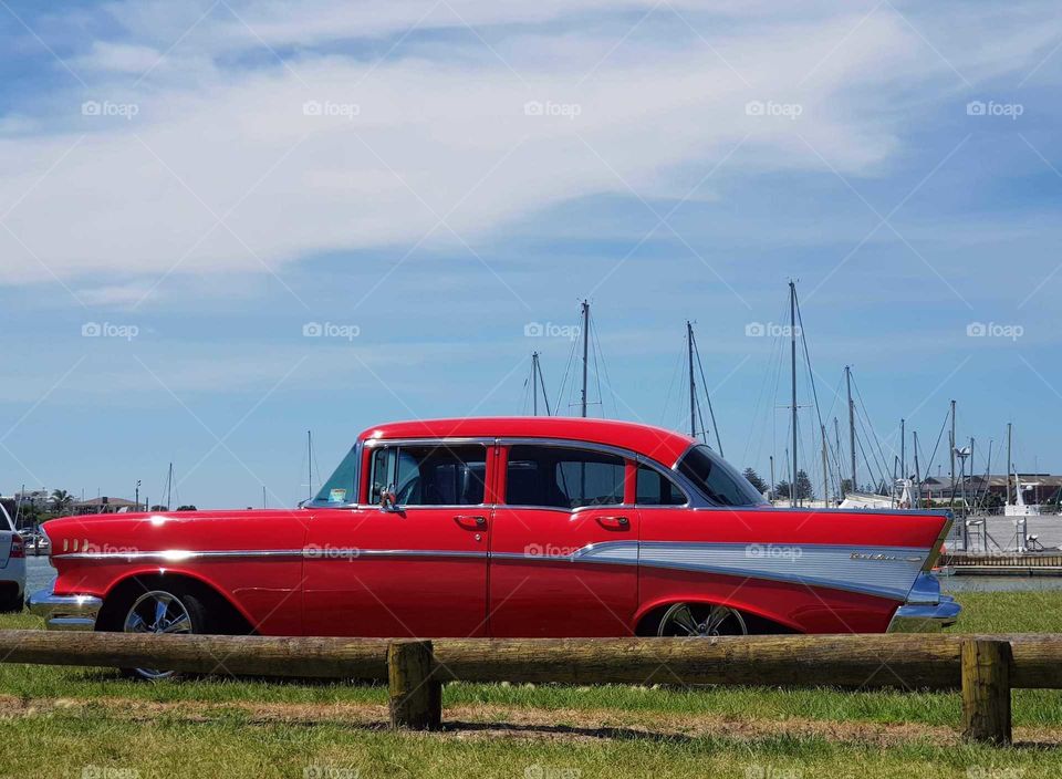 Old school red classic car. Parked next to the iron pot which is where the boat's sit tied awaiting a sail out to sea.