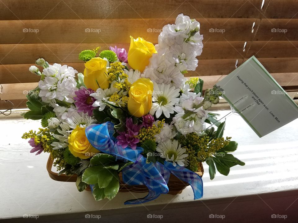 A beautiful basket of flowers,  with roses and daisies,  sent to wish someone well in a hard time.