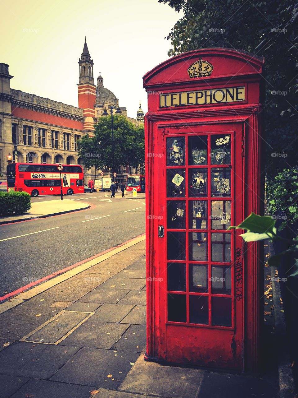 You are in London. Red telephone box and bus by the Victoria and Albert Museum, South Kensington, England.