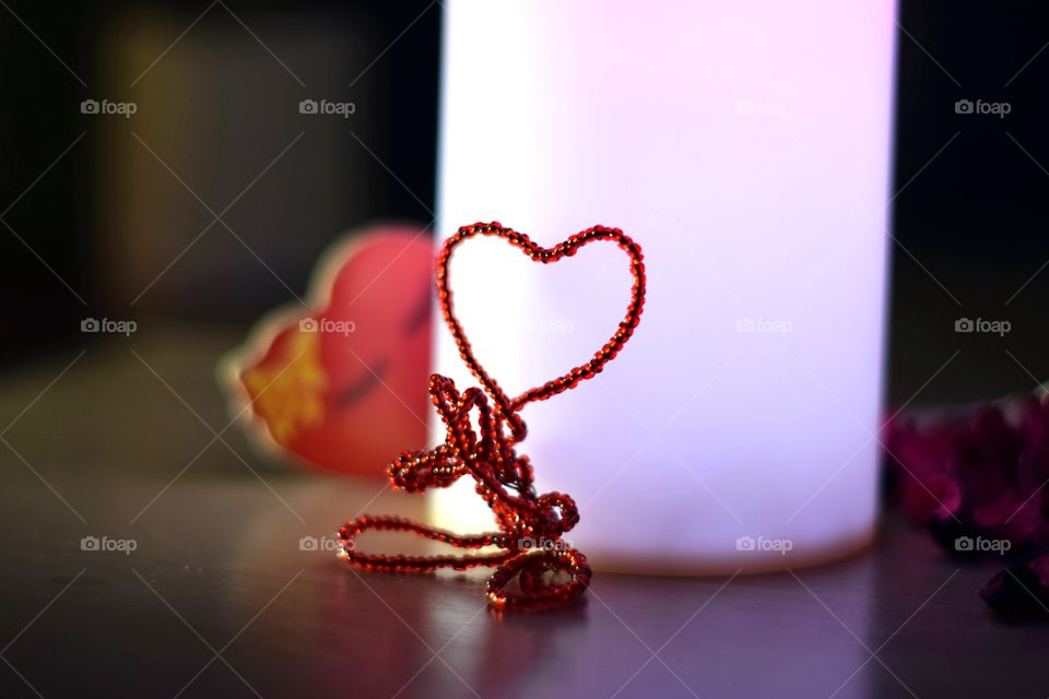 Red bead heart shape. Romantic scene on the table with led candles.