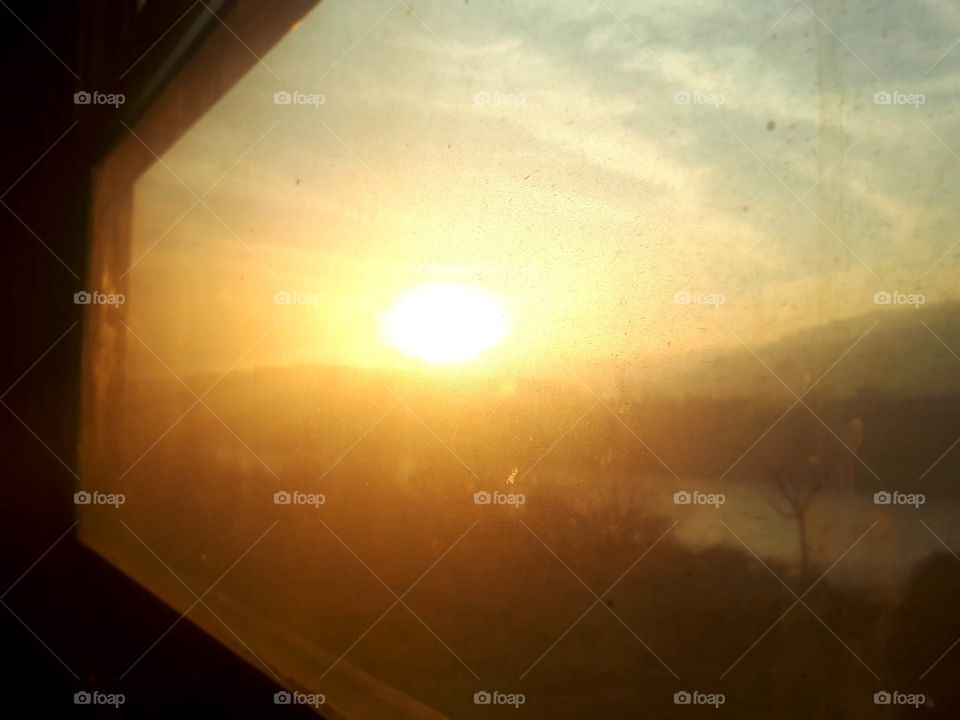 a view of the sunset through the window of the old passenger wagon