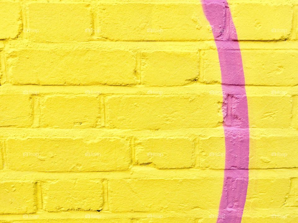 Bright yellow brick wall with a pink line
