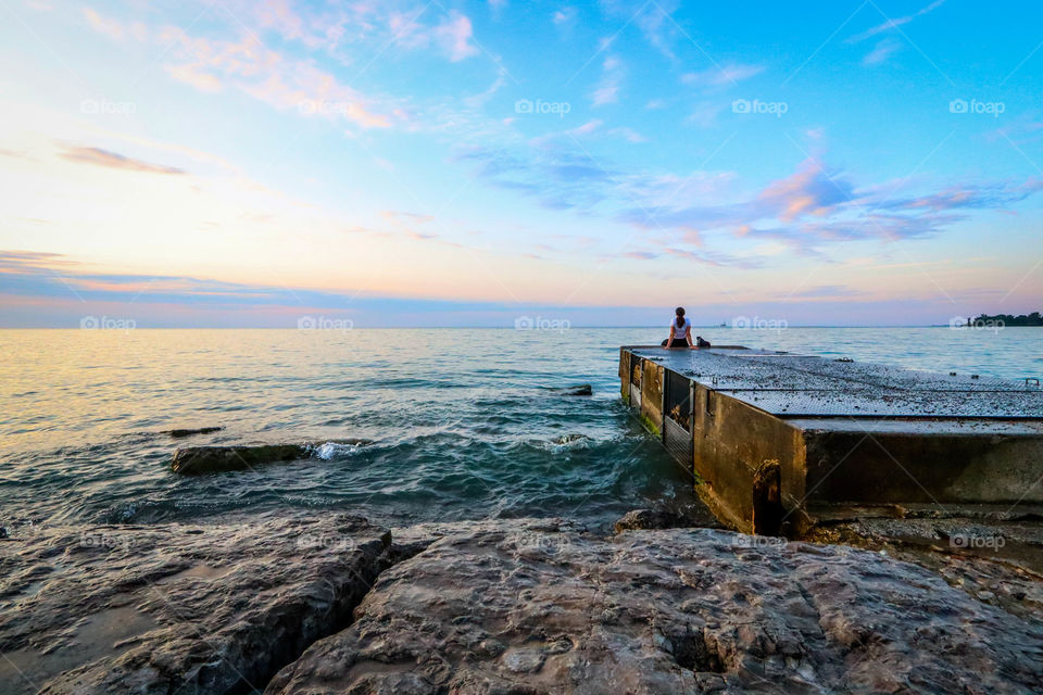 Woman is meeting a wonderful sunrise sitting on a pier