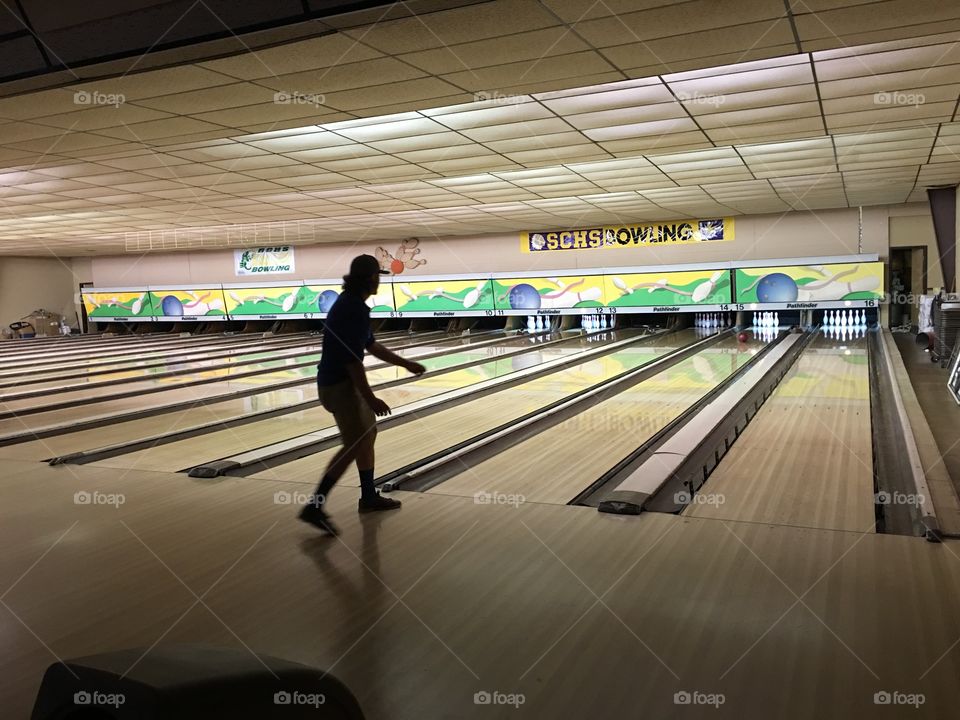 Silhouette of guy bowling in bowling alley