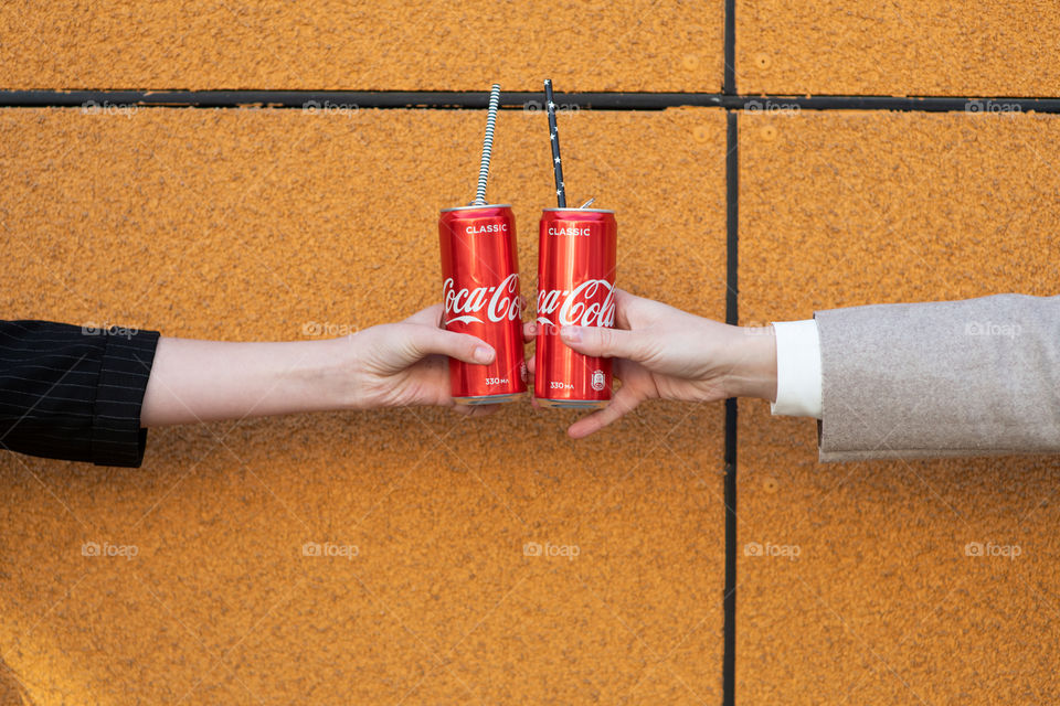 Two hands holds two red Coca-Cola cans