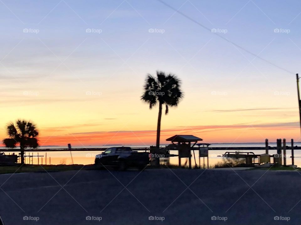 Early morning sunrise over beach ocean water in Eastpoint Florida road trip vacation palm tree fishing scenic