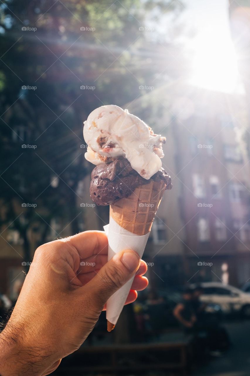 hand holds up a two ICE cream cone